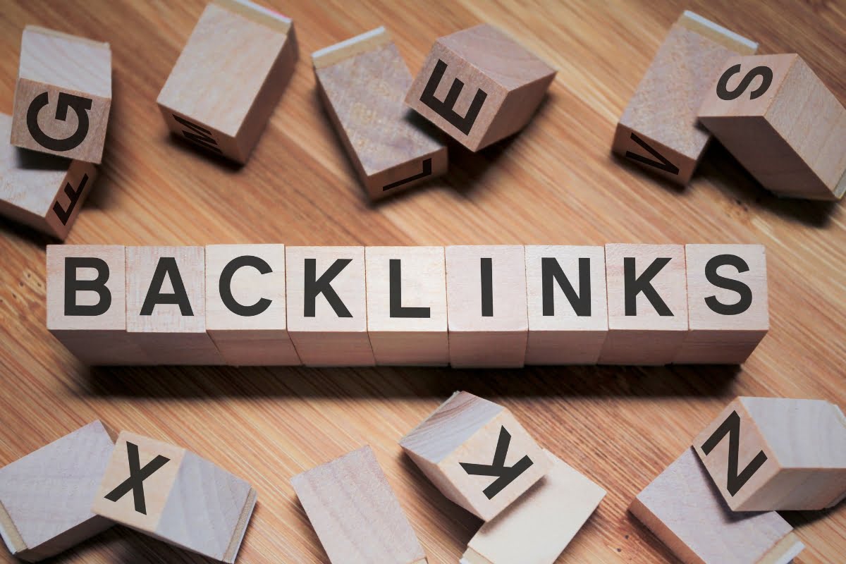 The first page ranking on Google prominently displays the word backlinks, surrounded by wooden blocks.