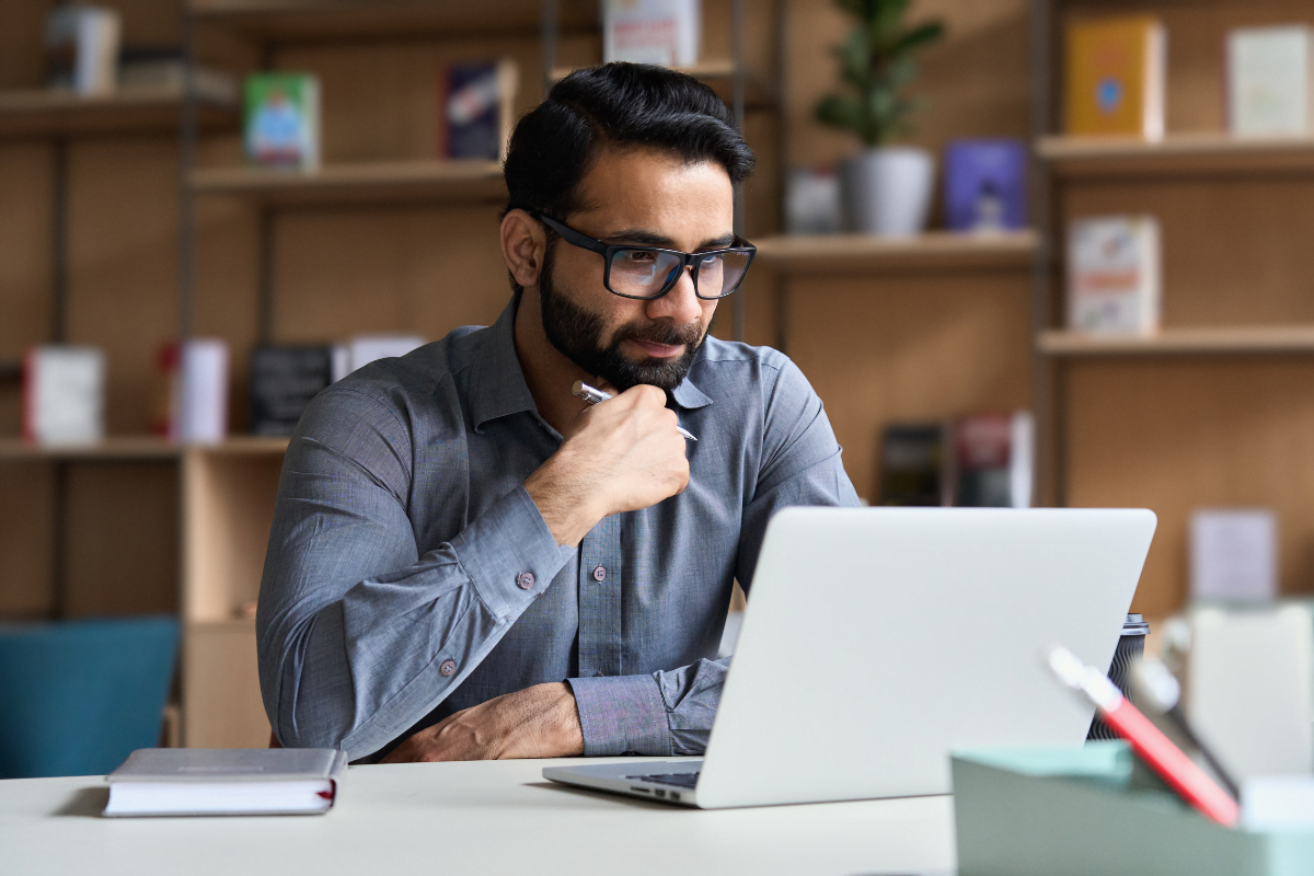 A man hiring an SEO consultant, sitting at a desk with a laptop in front of him.