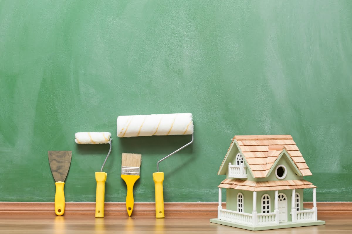 A home improvement business showcasing a house with paint brushes and paint rollers displayed on a blackboard.