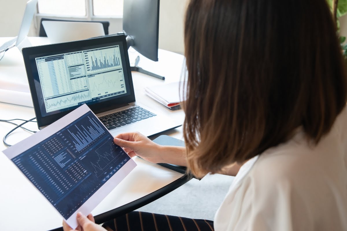 A woman is sitting at a desk with a laptop and a tablet, likely working for a home improvement marketing agency.