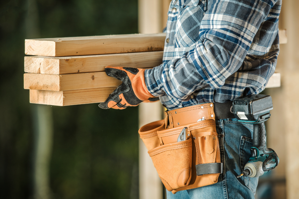 A construction worker using HomeAdvisor for contractors is holding a few pieces of wood.