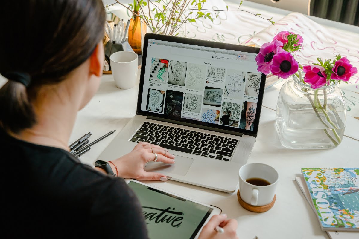 A woman sitting at a desk with a laptop and a tablet, learning how to optimize images for web.