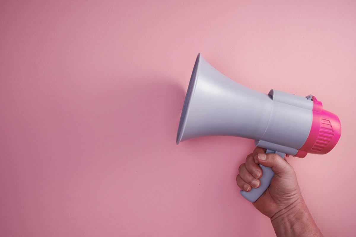 A hand holding a megaphone promoting local HVAC service ads on a pink background.