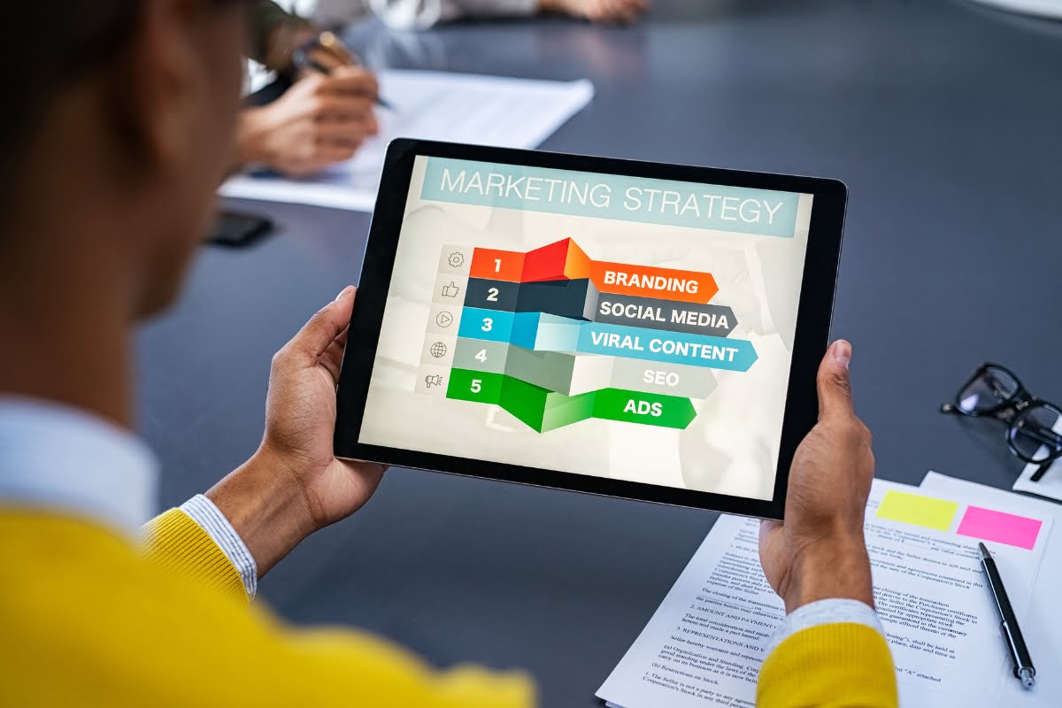 A man conducting keyword research by holding a tablet with marketing strategy and keyword research tips displayed on it.