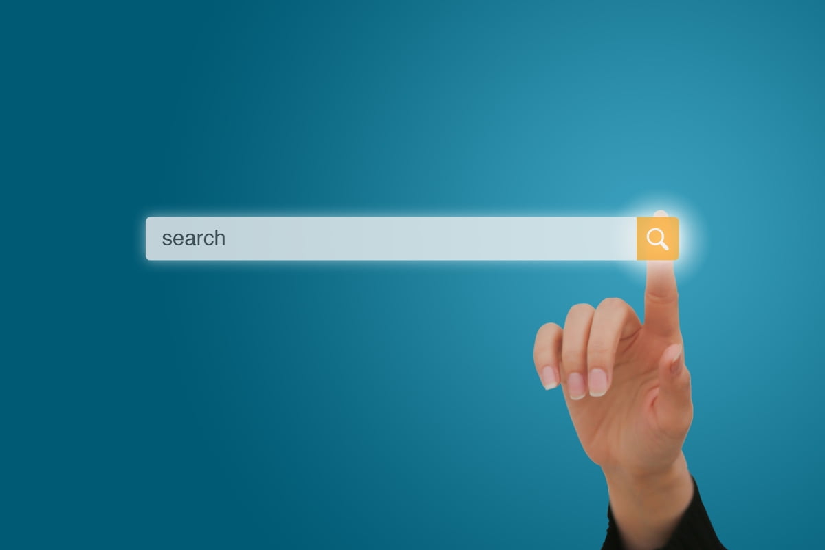 A hand is pointing at a search button on a blue background, providing keyword research tips.