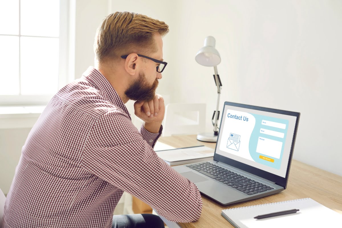 A man sitting at a desk, focused on his laptop screen for improved landing page conversions.