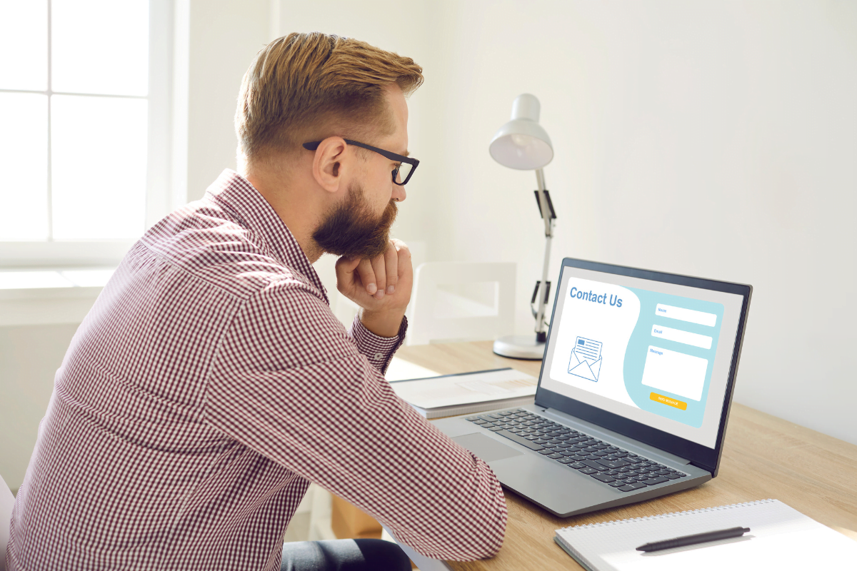 A man sitting at a desk, analyzing a laptop screen while optimizing landing pages for maximum conversion rates.