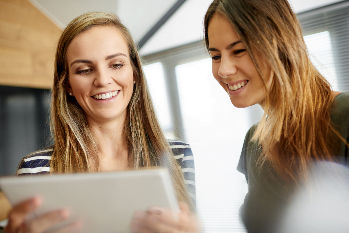 Two women looking at a tablet computer while discussing landing pages that convert.