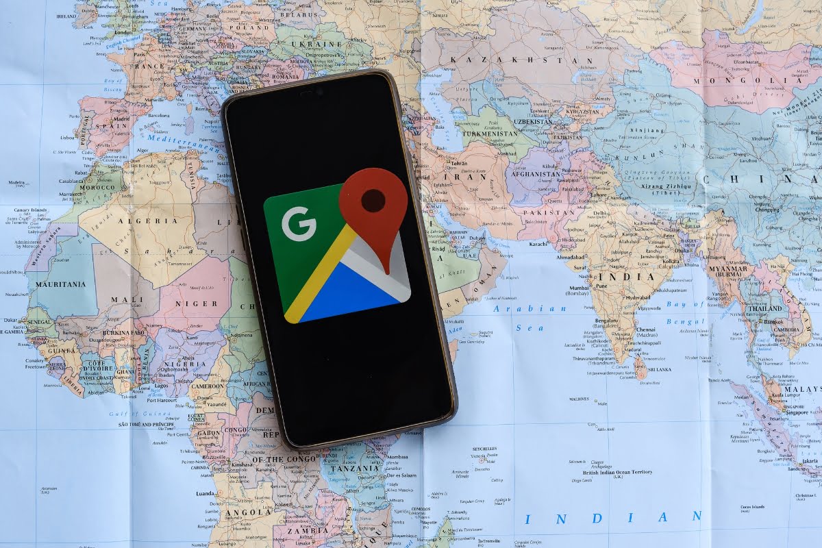 A smartphone with local business on Google Maps displayed on a world map.