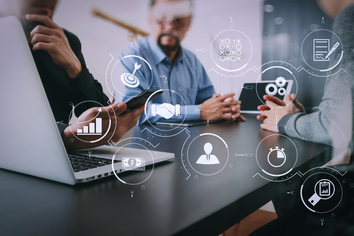 A group of people sitting around a table discussing the benefits of marketing automation.