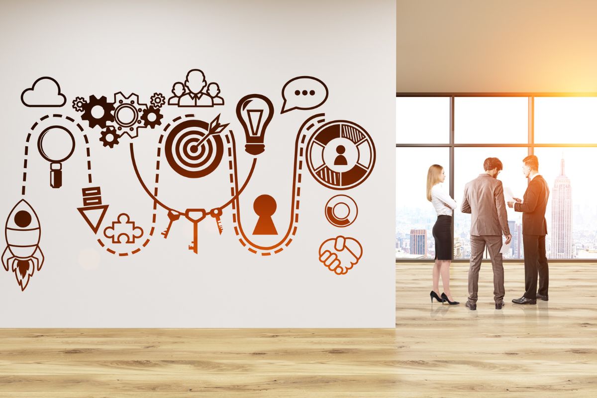 A group of business people standing in front of a wall, discussing marketing strategies for startups.