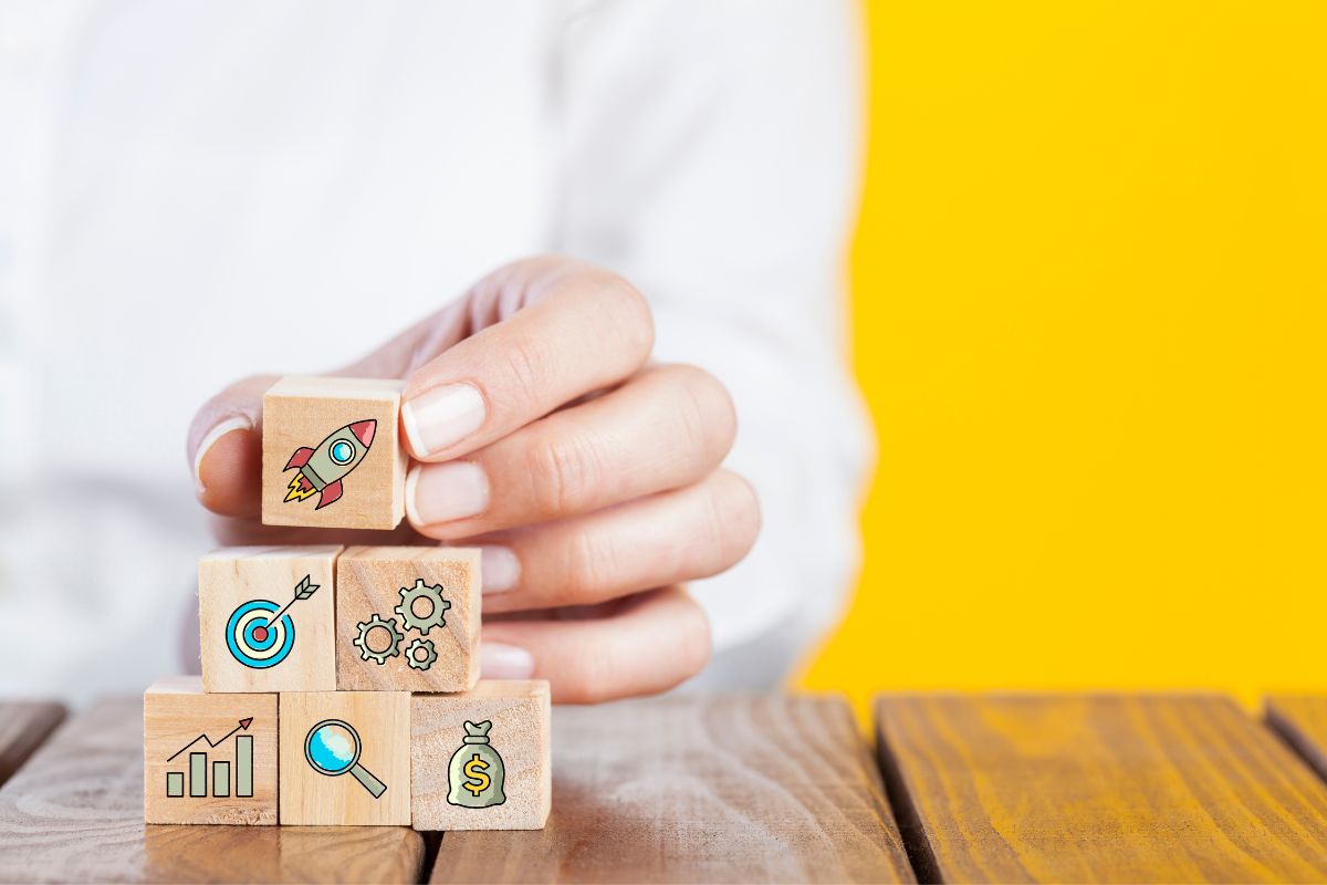 A woman showcasing innovative marketing strategies for startups by confidently holding wooden blocks adorned with business icons.