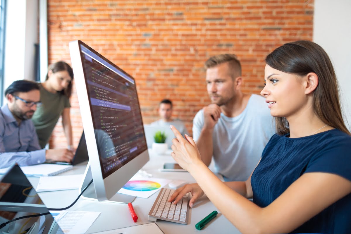 A group of people redesigning a website on a computer in an office.