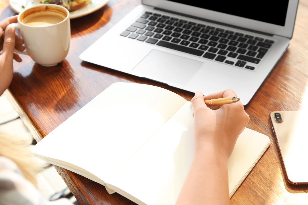 A woman writing in a notebook, focusing on SEO for electricians.