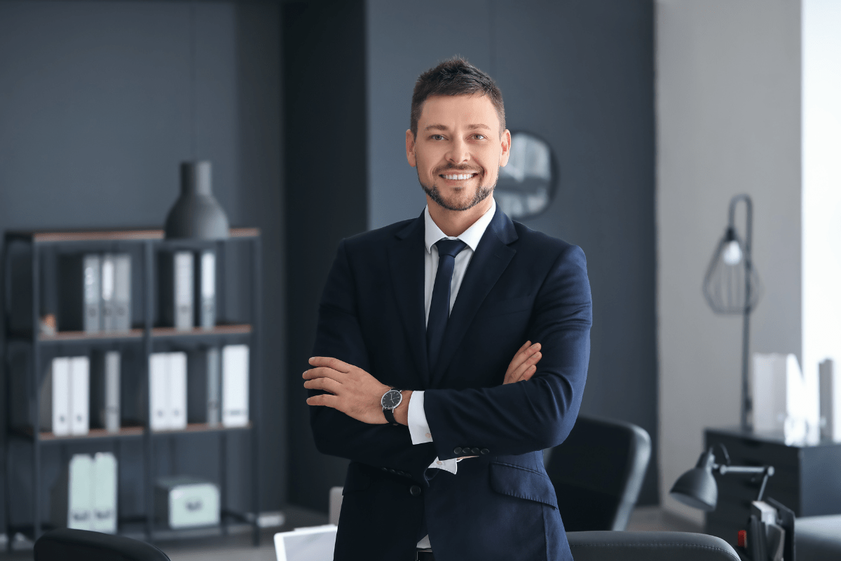 A smiling lawyer in a suit standing in an office, demonstrating professionalism.