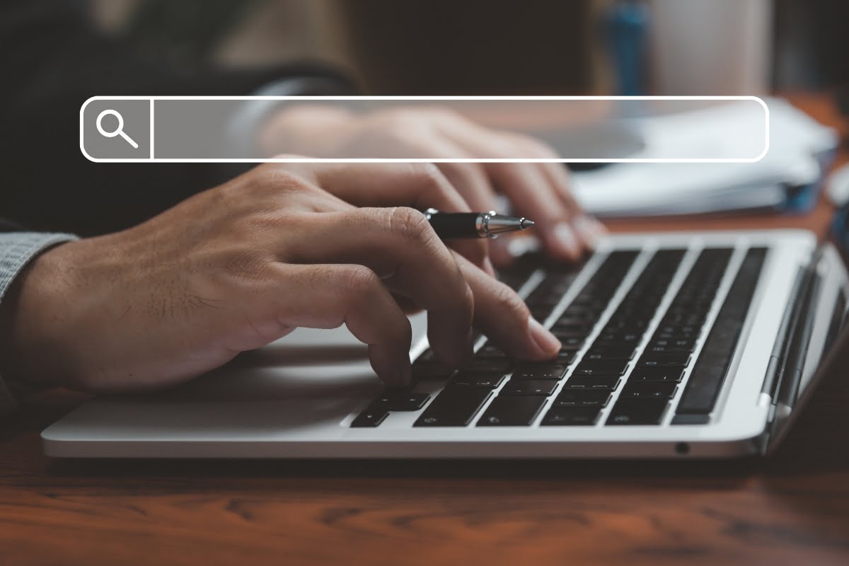 A man engaged in web design, skillfully typing on a laptop with a search bar visible in the background.