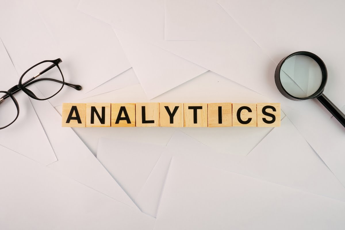 The word analytics spelled out in wooden blocks with a magnifying glass.