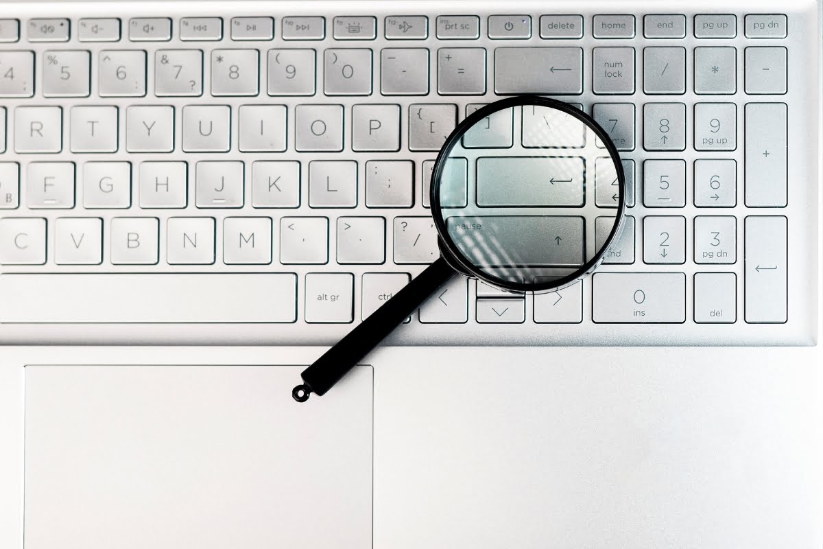 A magnifying glass on top of a white keyboard, symbolizing the importance of SEO in digital marketing.