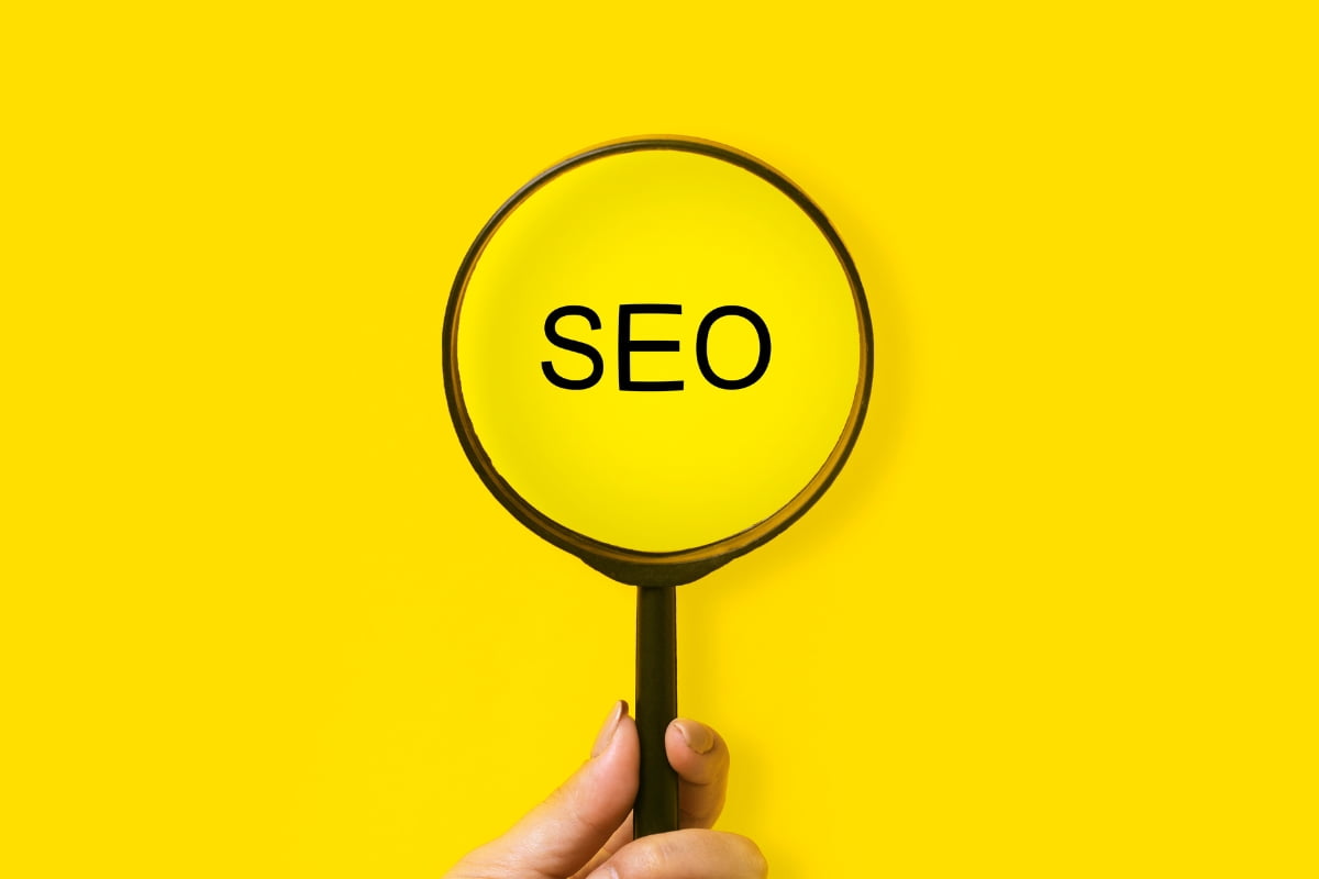 An individual holding a magnifying glass with the word SEO clearly visible, emphasizing its importance in digital marketing.