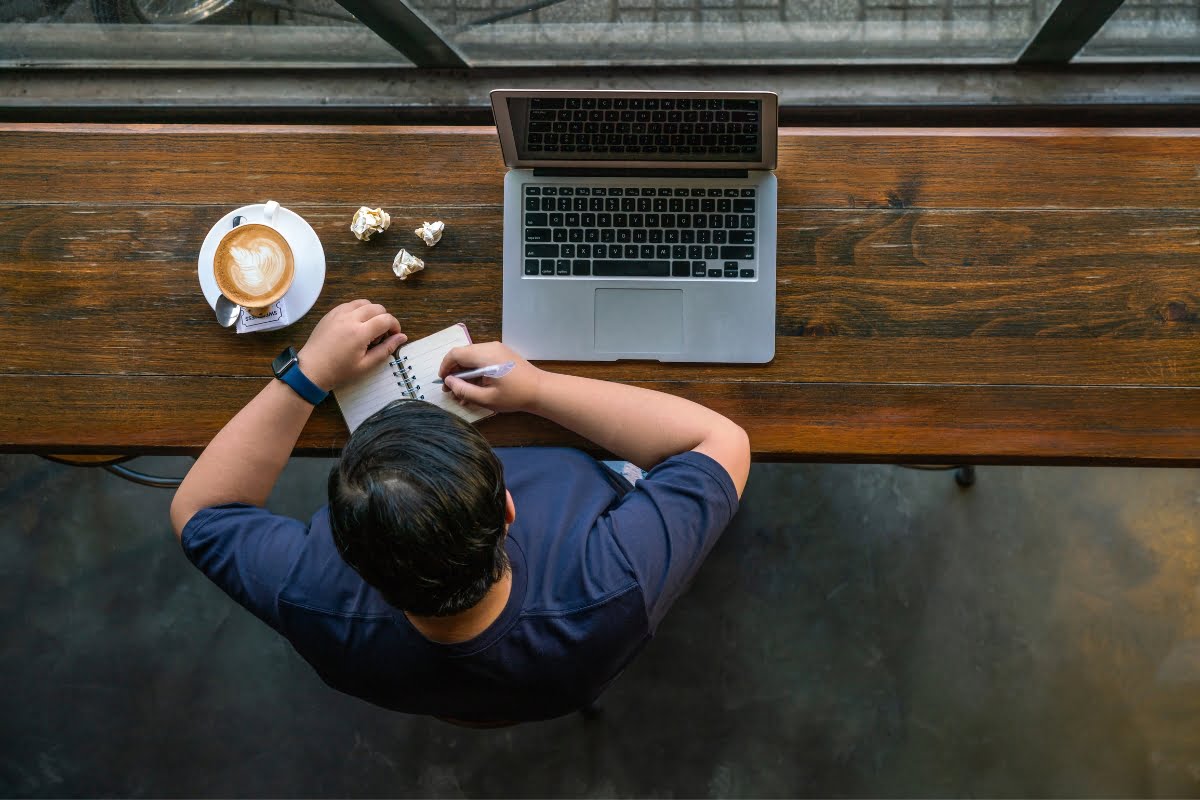 SEO: A man working at a table with a laptop and coffee - optimizing productivity!