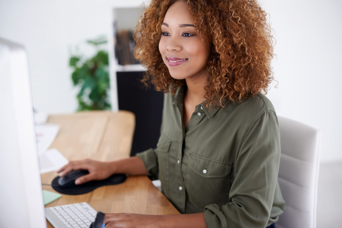 A young woman utilizing tools for email marketing while sitting at a desk in front of a computer.