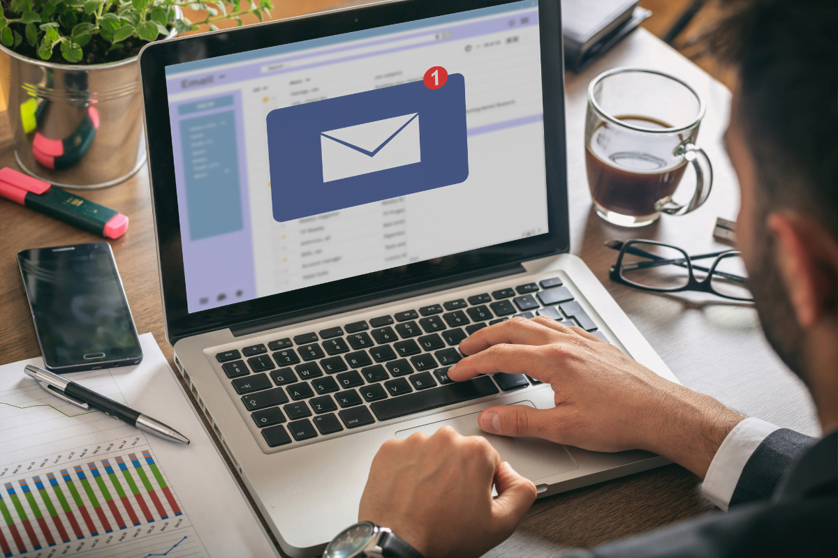 A man is using a laptop to access an email icon, leveraging tools for email marketing.