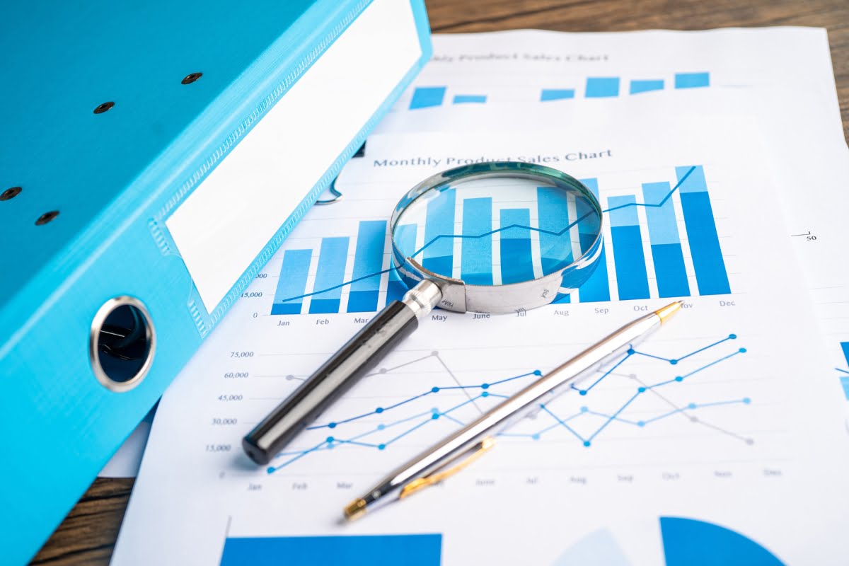 A magnifying glass on top of a blue folder with graphs and charts, reflecting the importance of thorough analysis in tree service marketing.