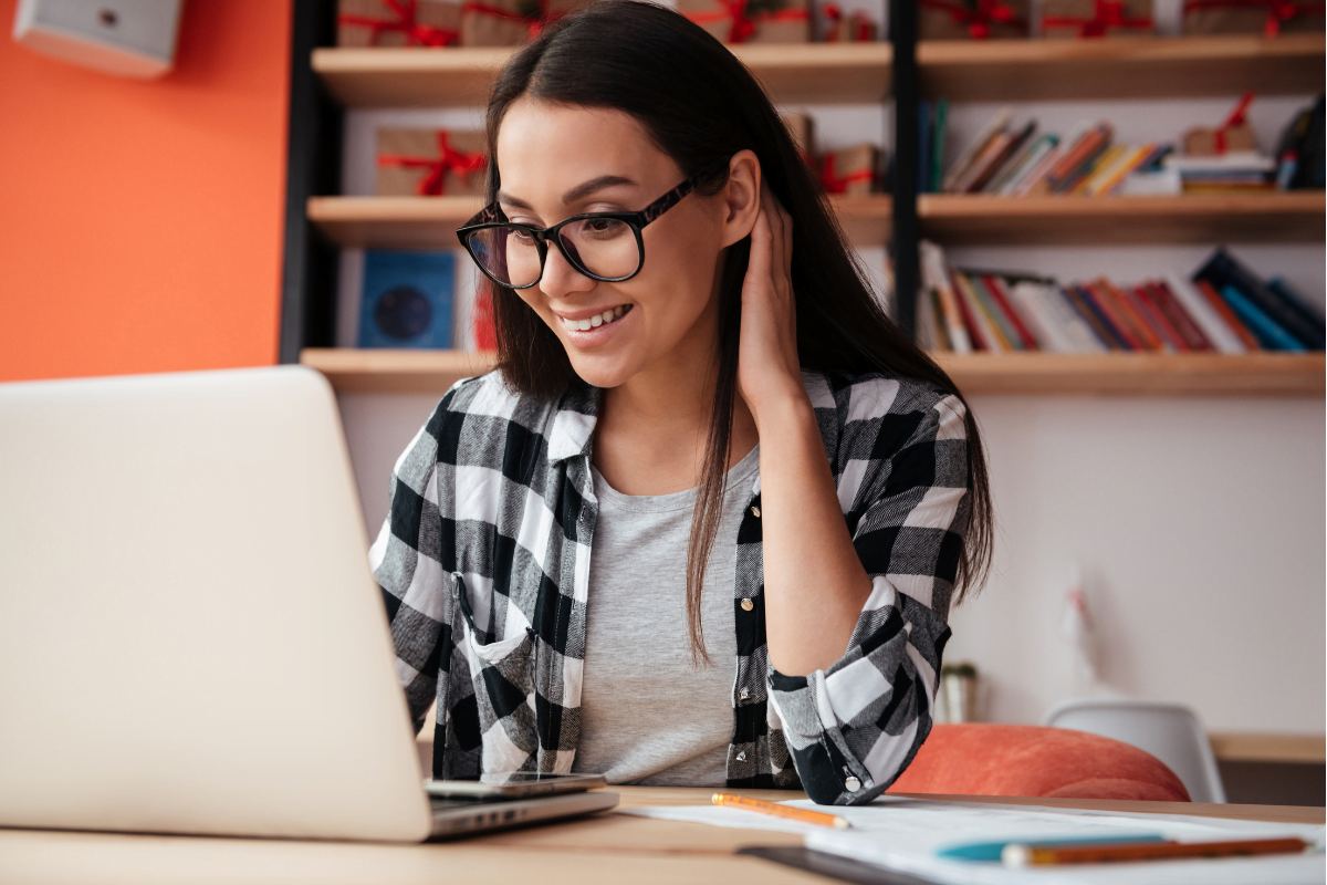 A woman wearing glasses is using a laptop to access some information on the internet.