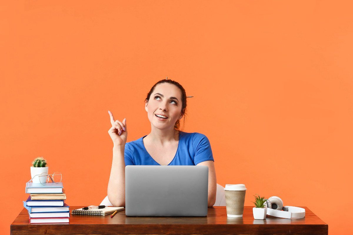 A woman sitting at a desk with a laptop on an orange background and comparing Wix vs WordPress for SEO.