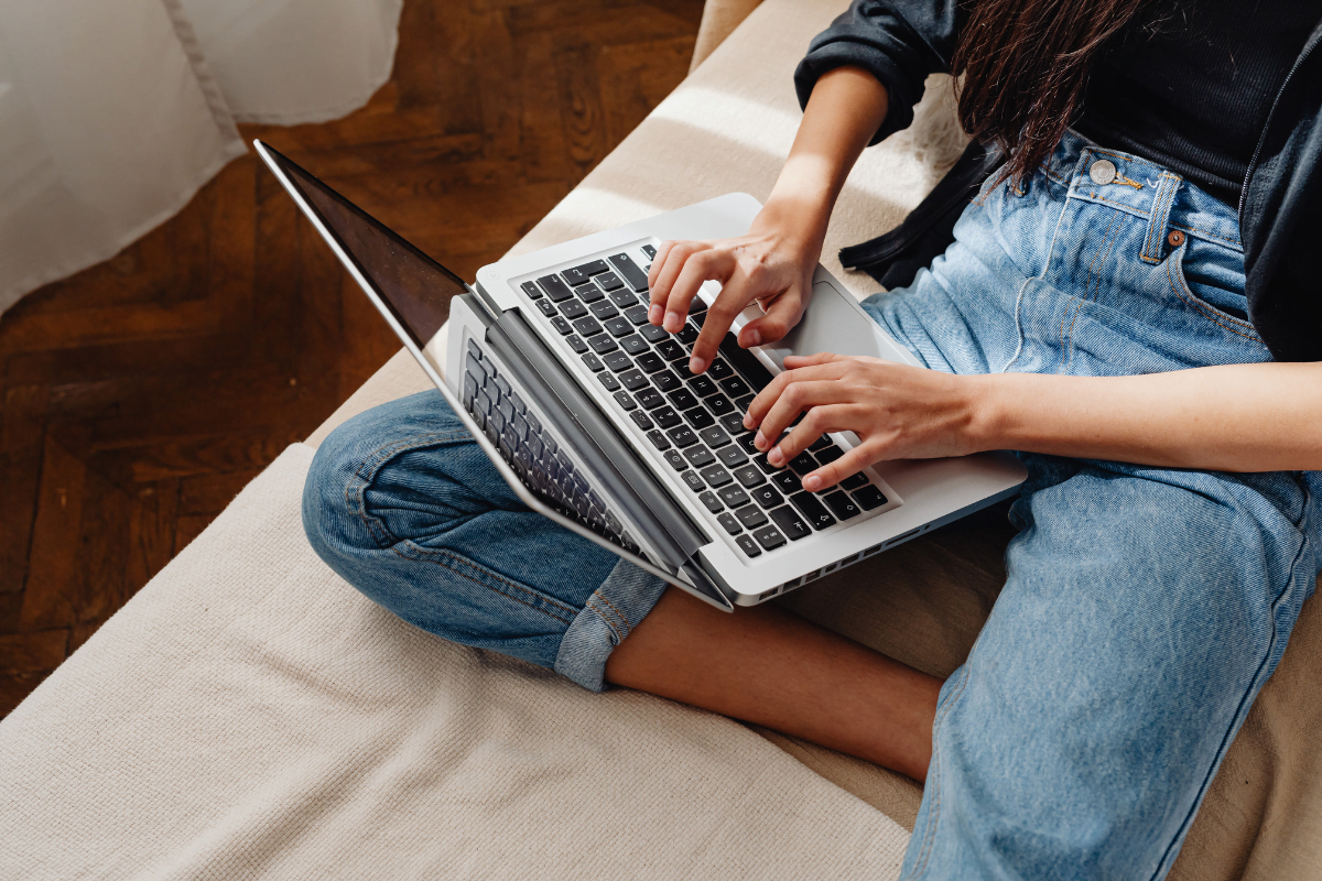 A woman is using a laptop on a couch.