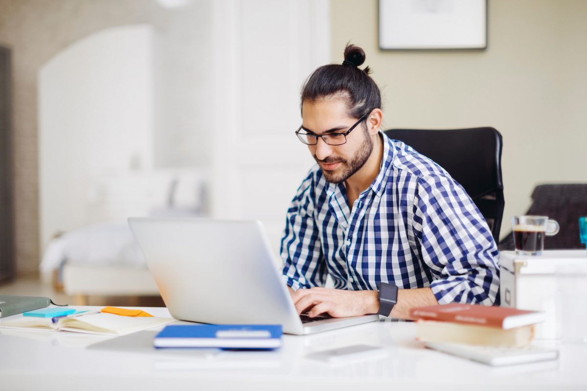 A man blogging for small businesses while working on a laptop in his home office.