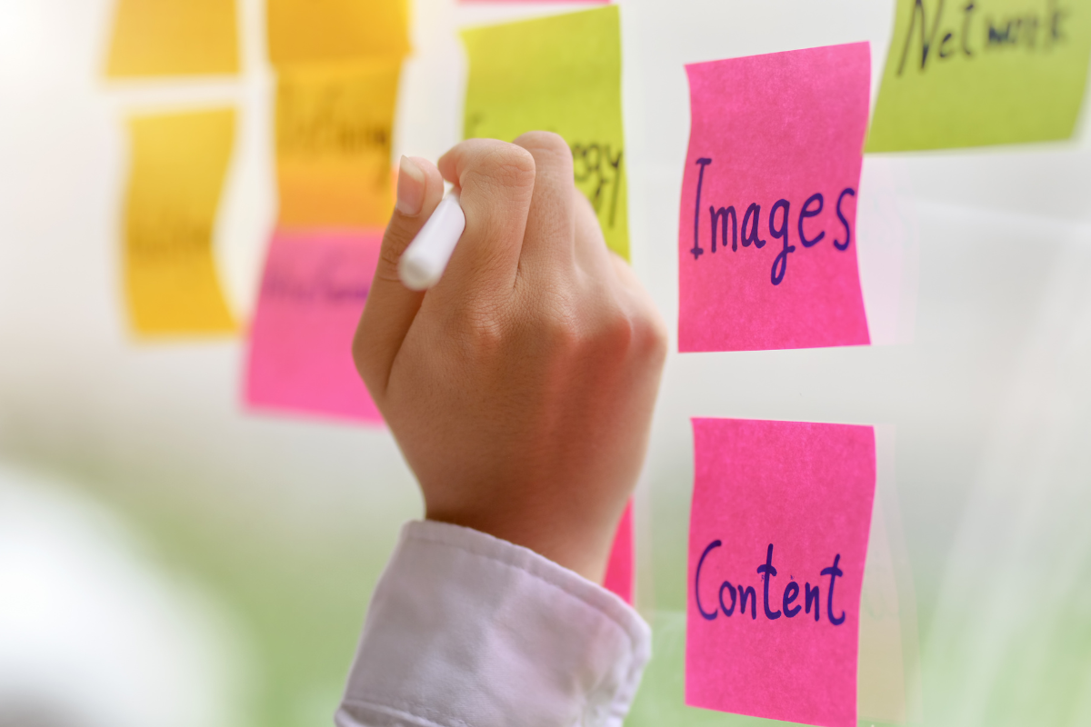 A person engaging in an effective strategy to boost search visibility by writing on a sticky note with images and content.