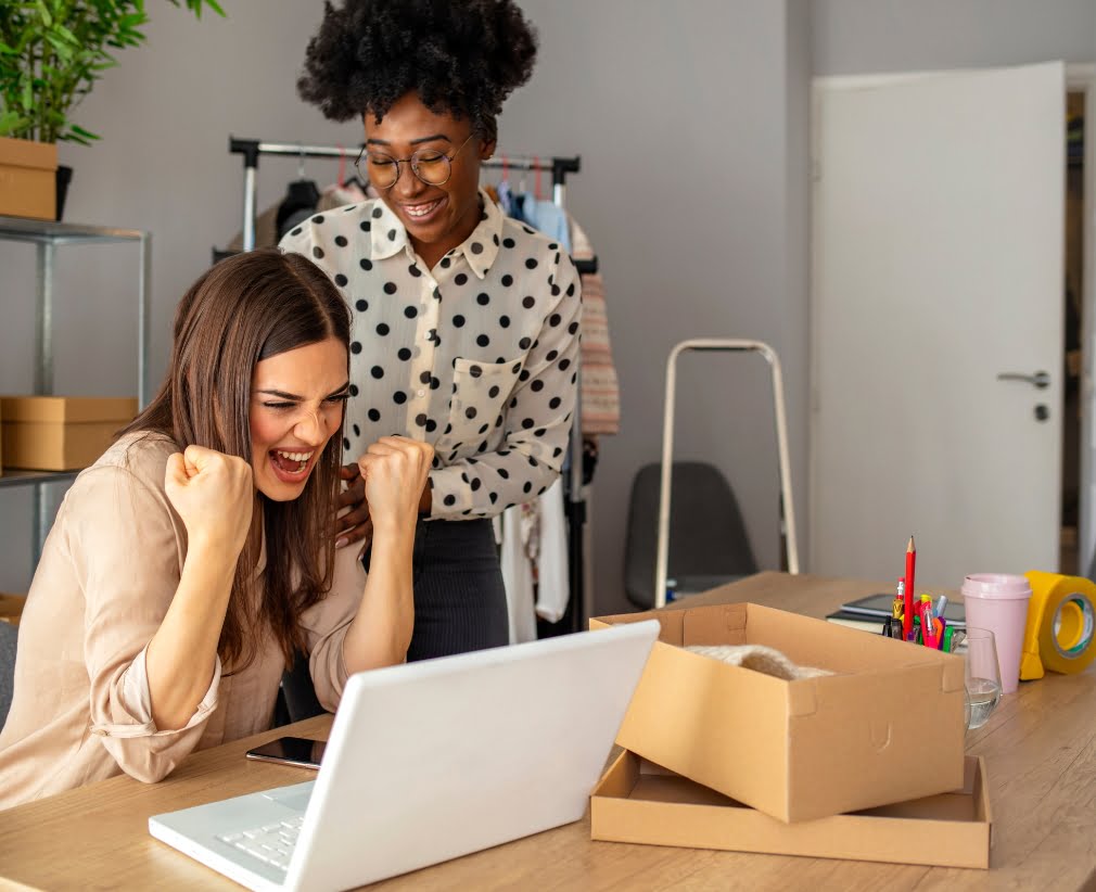 Two business women looking at their crm in an office excited about growing their business.