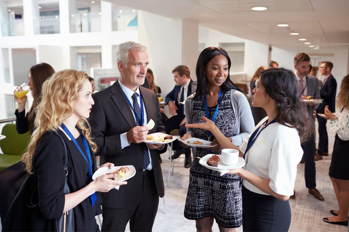 A group of business people at a networking event, connecting with potential catering clients.