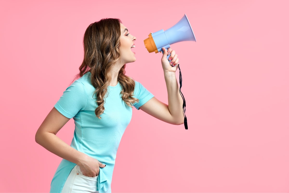 A young woman shouting into a megaphone is attracting catering clients on a pink background.