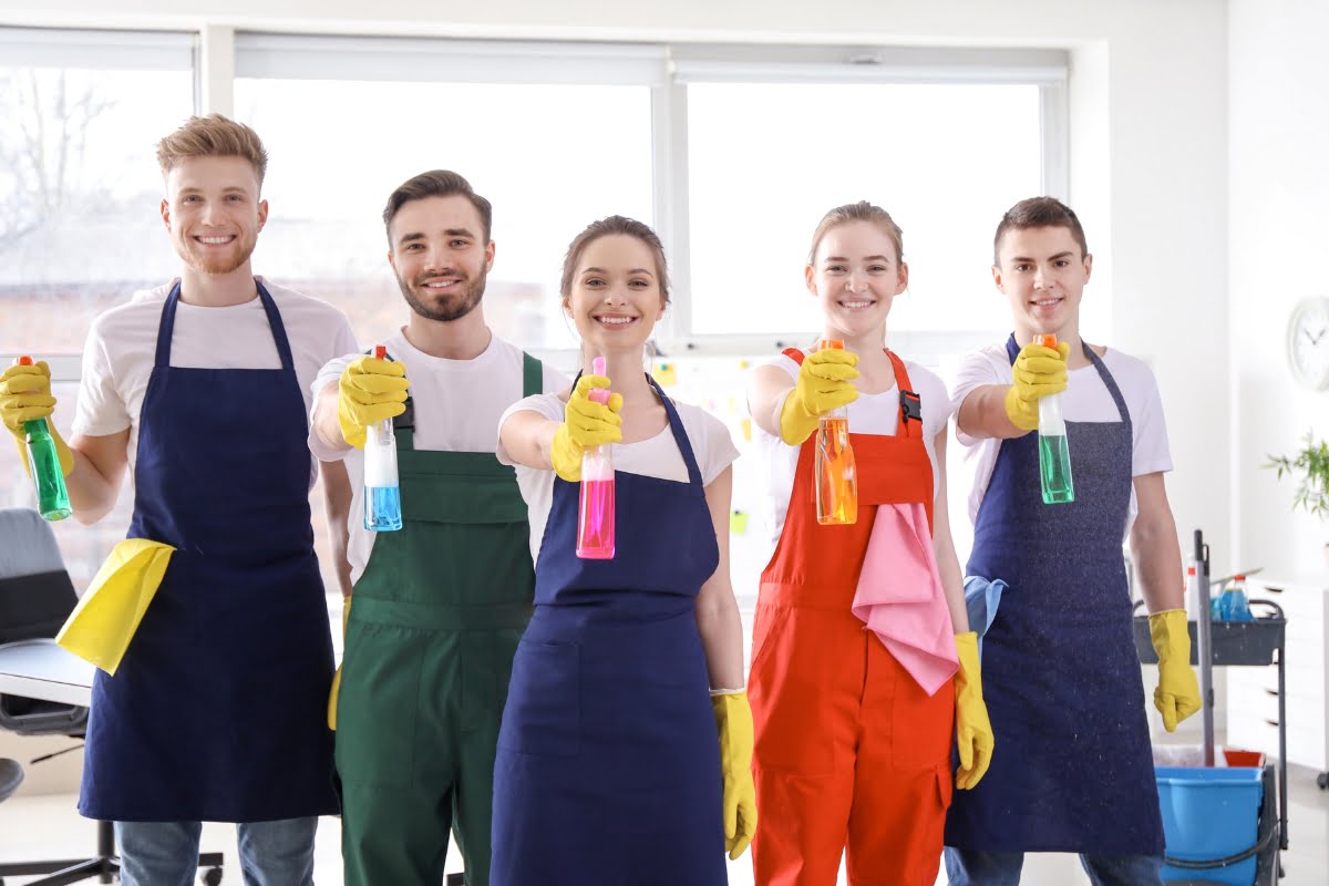 A group of people in aprons showcasing cleaning supplies for advertising ideas.