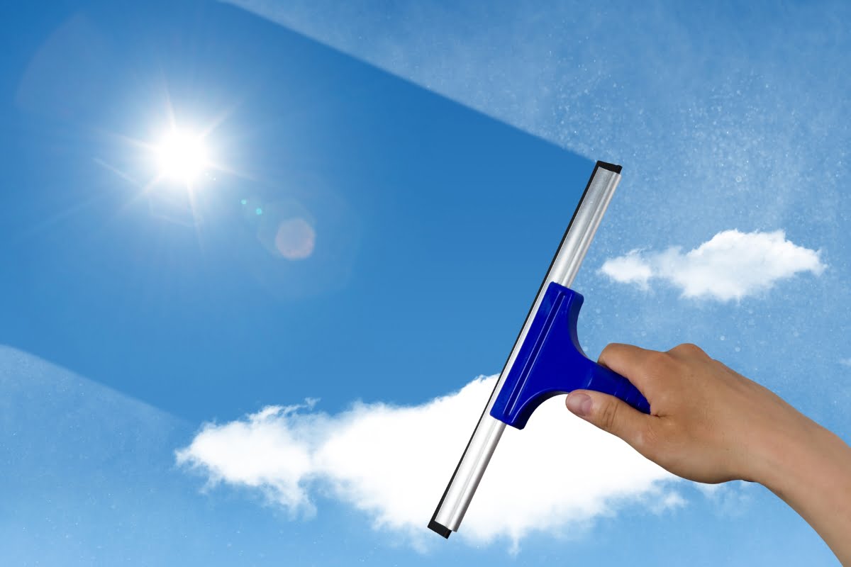 A hand holding a blue window cleaning tool, advertising cleaning ideas.