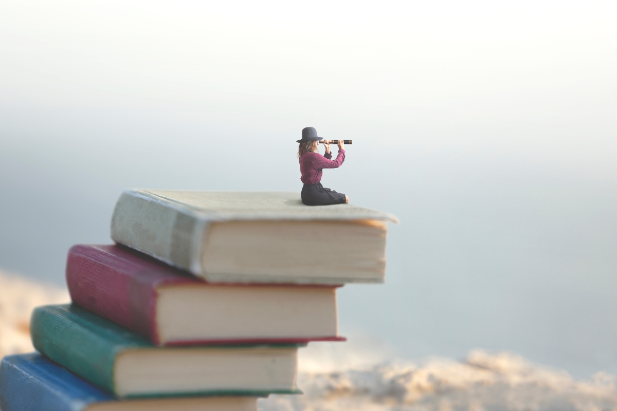 A person is standing on top of a stack of books, demonstrating a creative content marketing strategy.