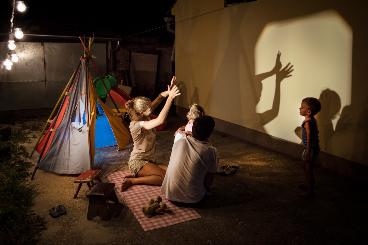 A group of people engaging in creative content ideas while playing with a teepee at night.