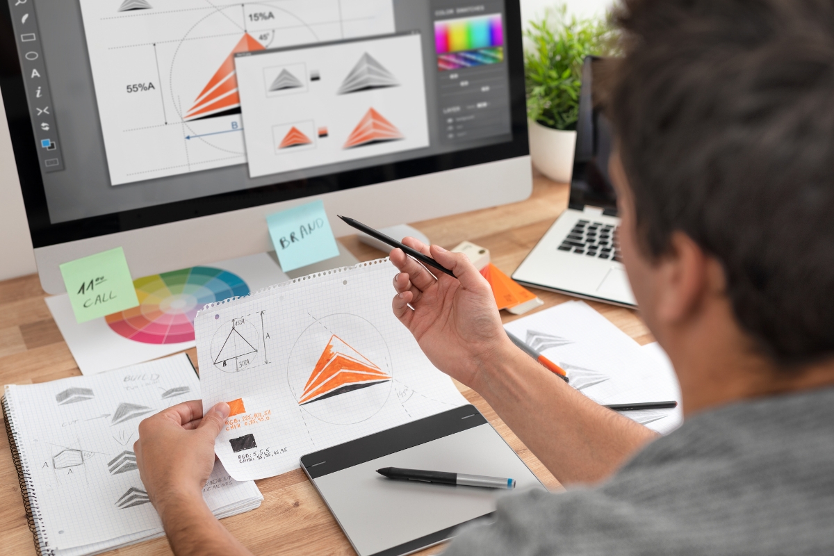 A man is working on a digital branding guide project at his desk.