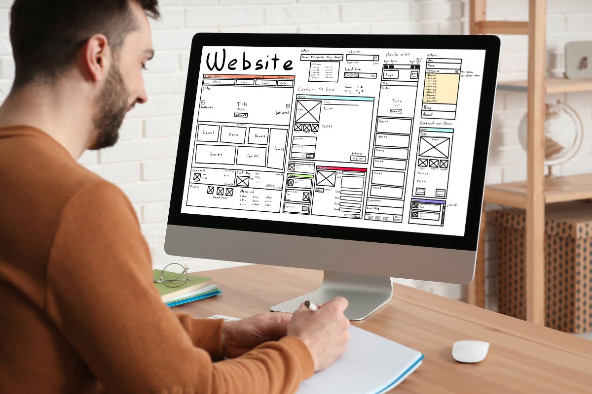 A man looking at a computer screen, analyzing a website design with the intention of maximizing sales.