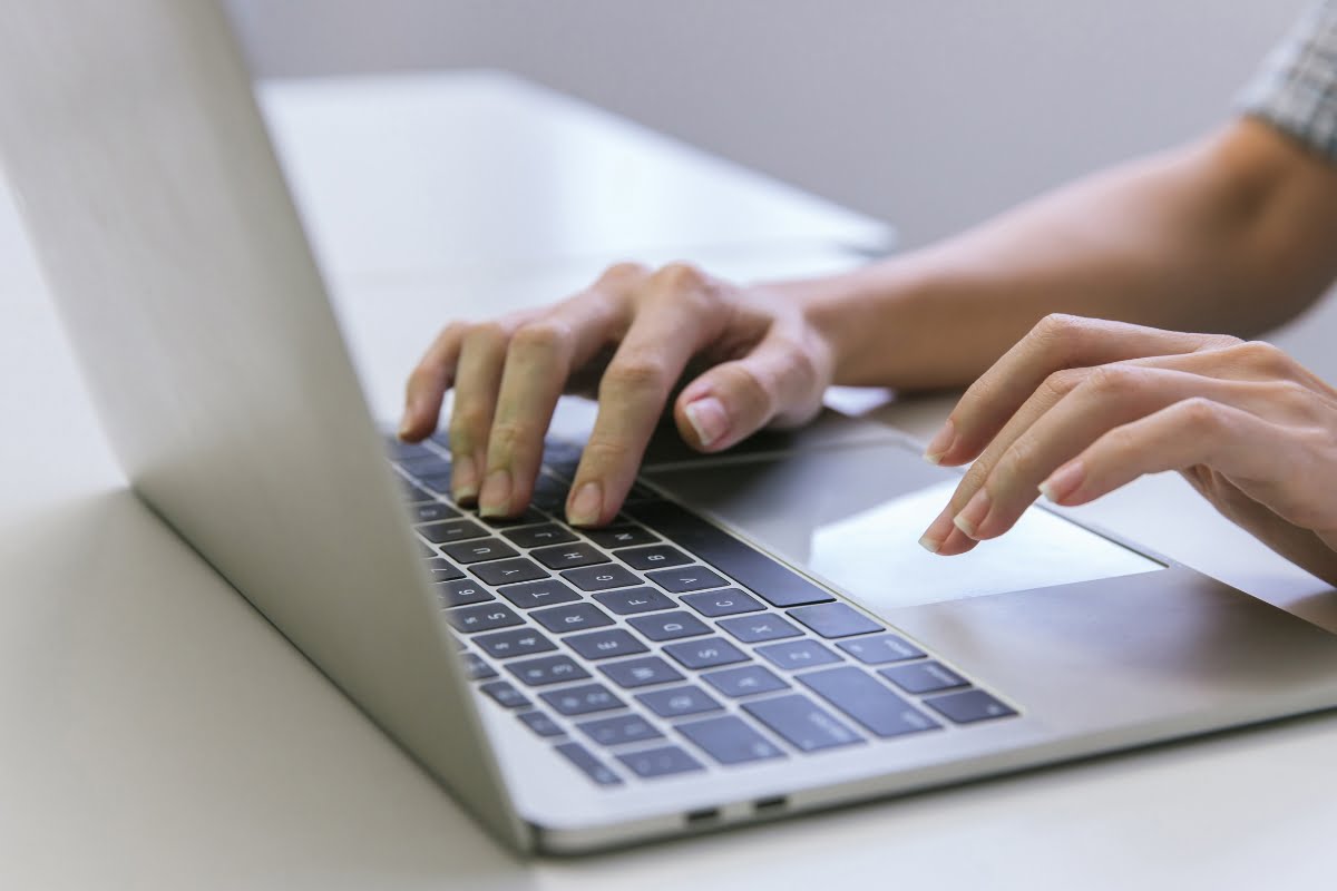 A person engaged in keyword clustering, typing on a laptop computer.