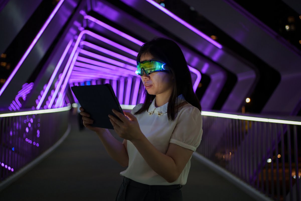 A woman experiencing metaverse using VR glasses on a bridge at night.