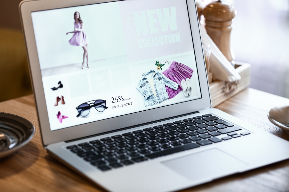 A laptop is sitting on a table displaying a stylish one page fashion website.