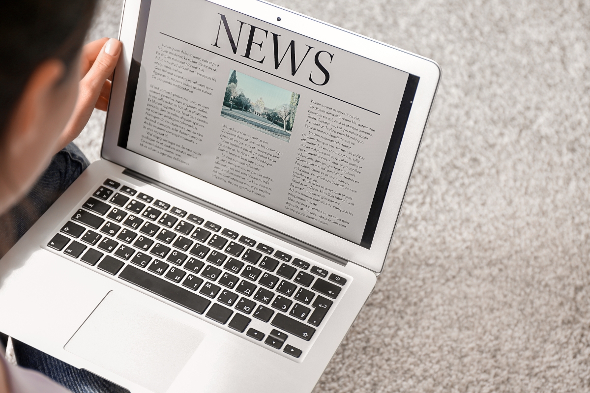 A woman using a laptop to browse a news article on a one page website.