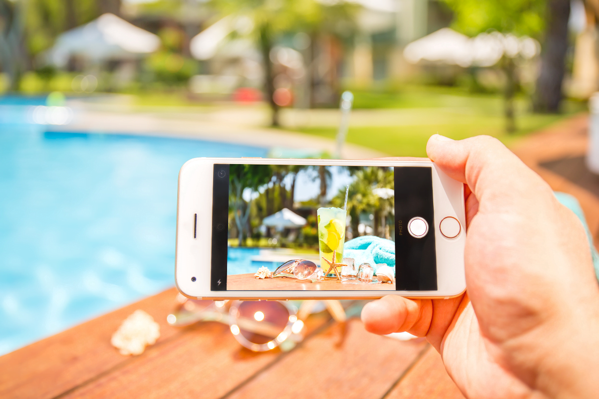 A person taking a picture of a pool with a cell phone for pool builder marketing.