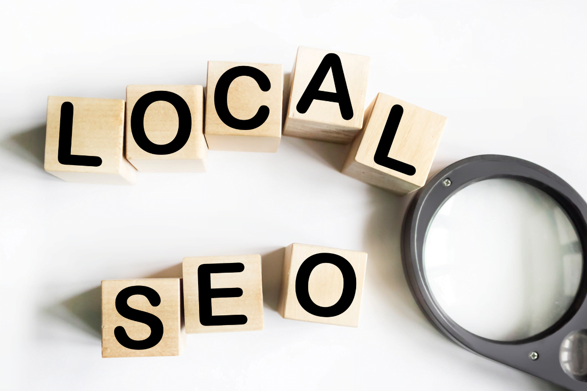 A magnifying glass and wooden blocks with the words "local seo" prominently displayed.