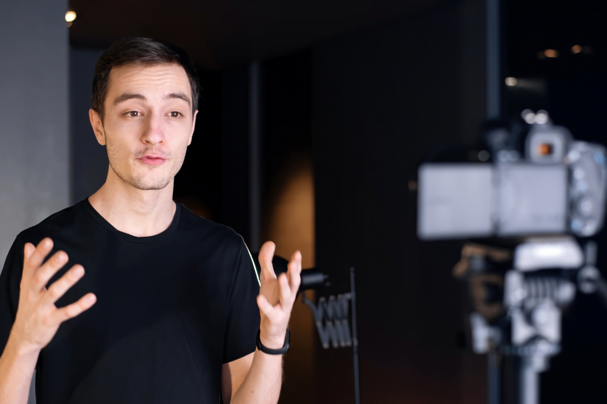 A man is strategically recording short video content in front of a camera.