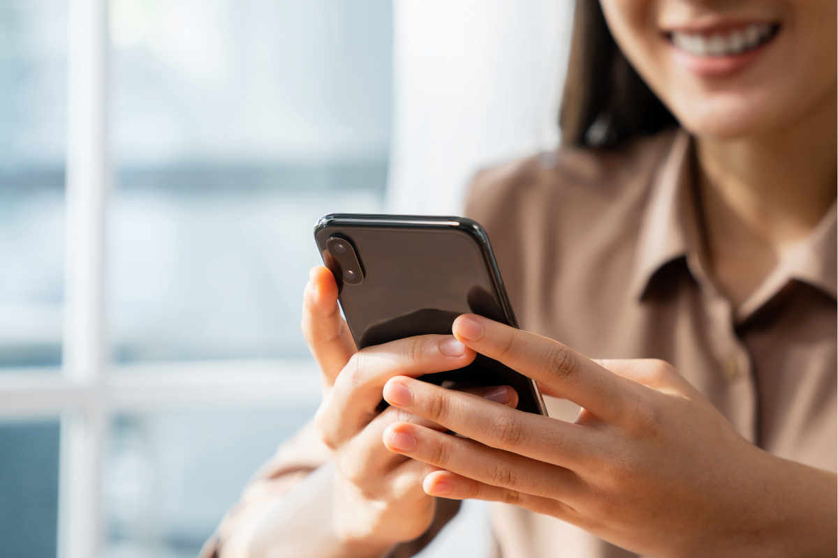 A woman holding a cell phone, utilizing social media for flooring companies.