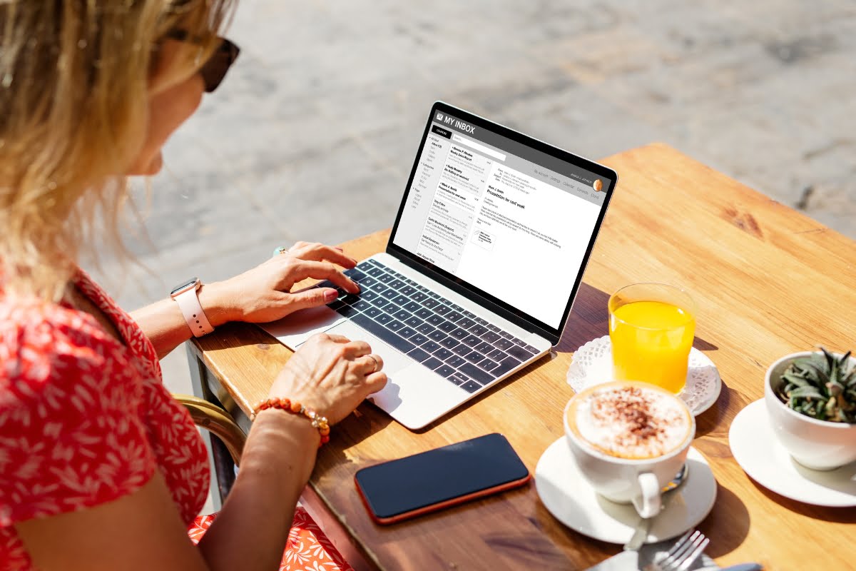 A woman sitting at a table with a laptop and a cup of coffee, engaged in spa email marketing.